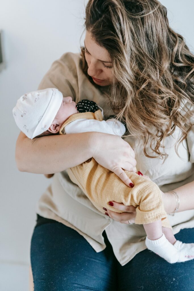 A tender moment of a mother holding her newborn baby indoors, showcasing warmth and affection.