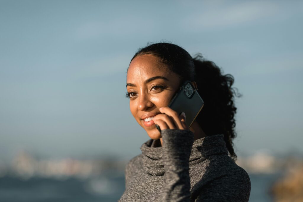 Young woman enjoying a phone call with a smartphone in a relaxed outdoor setting.