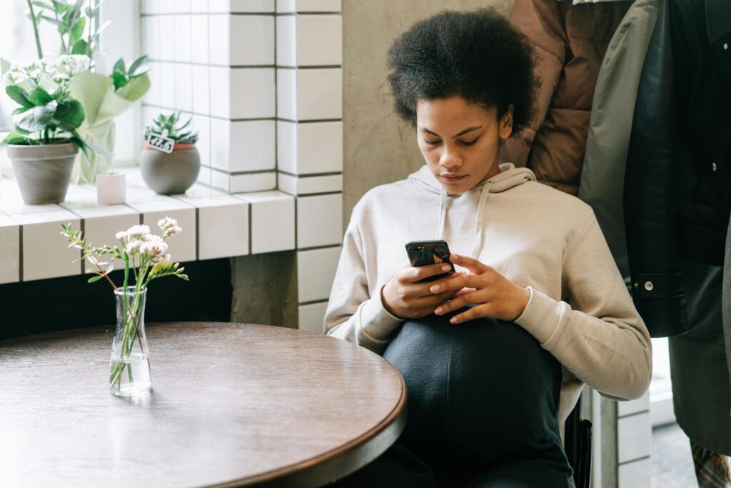 Pregnant woman in a café using a smartphone, enjoying a peaceful moment indoors.